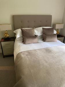 um quarto com uma cama grande com almofadas e 2 candeeiros em Gleneagles Holiday Home em Auchterarder