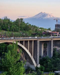 Olympia Garden Hotel في يريفان: جسر فوق نهر مع جبل في الخلفية