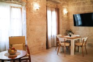 een woonkamer met een tafel en stoelen en een televisie bij Sessa's Palace in Korčula
