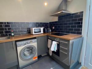 a kitchen with a washing machine and a microwave at Roundhay Apartments in Leeds