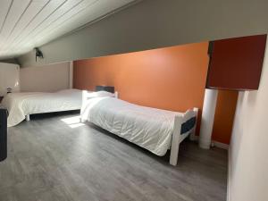 1 dormitorio con 2 camas y pared de color naranja en Capbreton Villa Patio 27m2 5 pers près port plages, en Capbreton