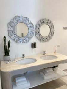 a bathroom with two sinks and mirrors on the wall at In centro unique rooms in Olbia