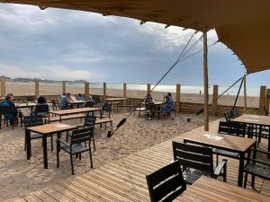 - un restaurant sur la plage avec des tables et des chaises dans l'établissement L'Air de la Mer, 2 chambres, 50m plage, parking, à Houlgate