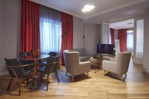 a living room with a table and chairs and a television at The Embassy Suites in Sofia