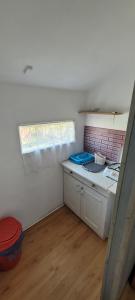 a small kitchen with a sink and a window at DOM BURSZTYNEK -domek drewniany in Junoszyno