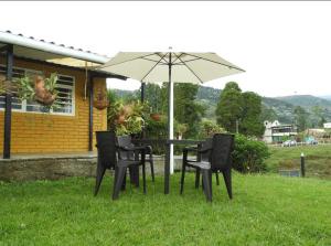 Hostal San Ramon في سانتا روزا دي كابال: طاولة وكراسي مع مظلة في العشب