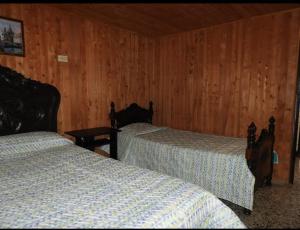 Habitación con 2 camas y paredes revestidas de madera. en Hostal San Ramon, en Santa Rosa de Cabal