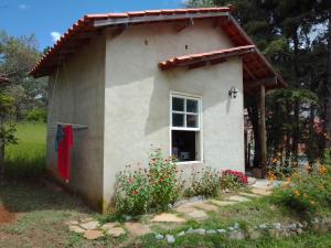 ein kleines Haus mit einer roten Tür und einem Fenster in der Unterkunft Chalé Caiçara in Carrancas