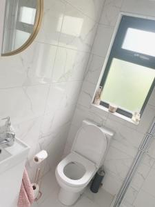 a white bathroom with a toilet and a window at Swan Cabin in Swanlinbar