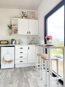 a kitchen with white cabinets and a table at Swan Cabin in Swanlinbar