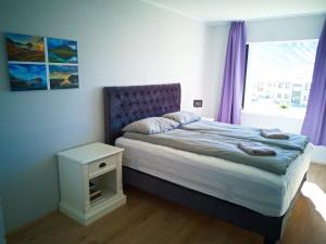 a bedroom with a bed and a window with purple curtains at Apartment with Amazing Mountain View in Bolungarvík