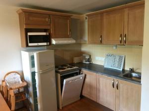 a kitchen with wooden cabinets and a white refrigerator at T2 bis duplex 6 couchages situé aux BOTTIERES in Saint-Pancrace