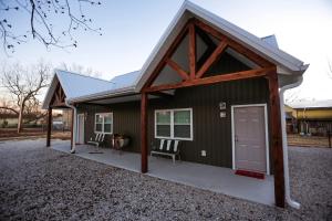a small green building with a door and two chairs at Knotty Squirrel Cabins in Mountain View