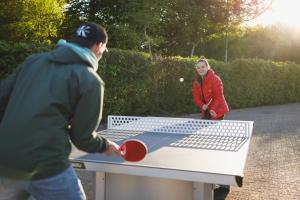 a man and woman playing a game of table tennis at Wereldse Bell Tenten met alpaca's in Paasloo