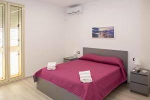 a bedroom with a large bed with a pink blanket at Endless Summer Apartment in Marina di Ragusa