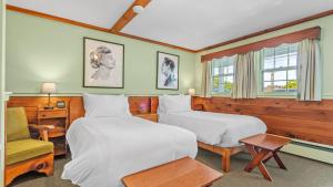 una habitación de hotel con 2 camas y una silla en Mid-Town Motel, en Boothbay Harbor