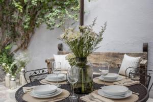 a table with plates and glasses and a vase with flowers at Casa Recreo King Suite Apartments in Centro, San Miguel de Allende in San Miguel de Allende