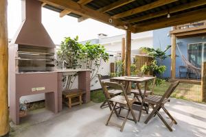 a patio with a table and chairs and an outdoor grill at Pousada Caminho Nômade in Praia do Rosa