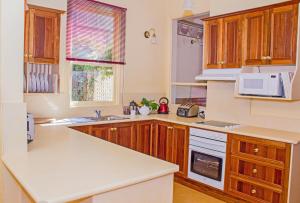 uma cozinha com armários de madeira e electrodomésticos brancos em The Duck House em Burnie