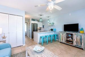 a living room with a kitchen and a bar with blue stools at Updated WATERFRONT, pool, tiki bar, boat ramp, etc in Marathon