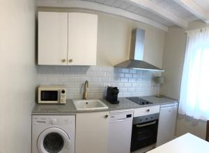 a white kitchen with a sink and a microwave at La casita de El Montan Baja in Avilés