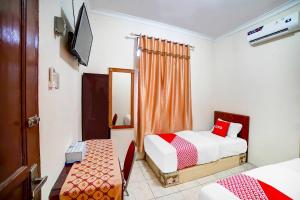 a hotel room with two beds and a television at OYO 91199 Felicia Homestay in Medan