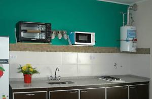 a kitchen with a sink and a microwave at Complejo Dolce Clementina in San Clemente del Tuyú