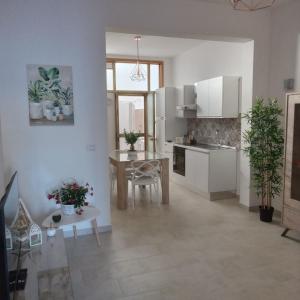 kuchnia z białymi szafkami i stołem z roślinami w obiekcie Casa Angelina Summer w mieście Casalabate