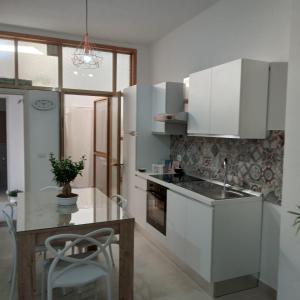 kuchnia z białymi szafkami i stołem z rośliną w obiekcie Casa Angelina Summer w mieście Casalabate
