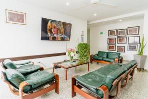 una sala de espera con sillas verdes y una mesa en Hotel Las Molas, en Apartadó