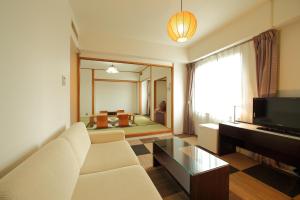 a living room with a white couch and a television at Select Royal Yatsushiro in Yatsushiro