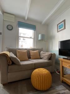 a living room with a couch and a television at 3 Bedroom Cottage minutes walk from town, harbour & Beaches. in St Ives