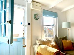 a living room with a couch and a clock on a wall at 3 Bedroom Cottage minutes walk from town, harbour & Beaches. in St Ives