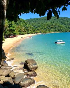 einen Strand mit Felsen und einem Boot im Wasser in der Unterkunft • Suíte Palmas • À Beira-Mar - Ilha Grande RJ® in Praia de Palmas