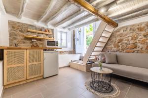 a kitchen and living room with a couch and a table at Pefkias Tiny Cottage in Skopelos Town