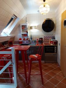 a kitchen with a red table and a red chair at Le paradis bleu in Bosville