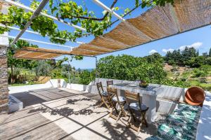 a patio with a table and chairs under a pergola at Pefkias Tiny Cottage in Skopelos Town