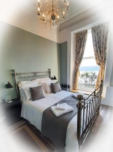 a bedroom with a bed with a chandelier and a window at Highlander House B&B in Rothesay