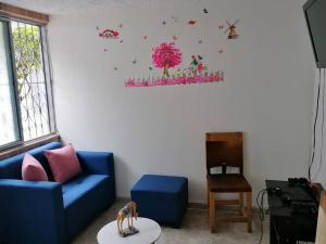 ein Wohnzimmer mit einem blauen Sofa und Blumen an der Wand in der Unterkunft Bienvenido a tu segundo hogar a dos cuadras del centro recreaciónal lagos club comfatolima in Ibagué