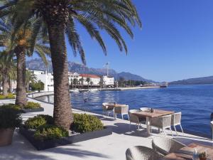 a patio with tables and chairs next to a body of water at un site calme et unique au Montenegro Loue des logements les pieds dans l eau avec plage privée en face de l ile Saint Marco in Tivat