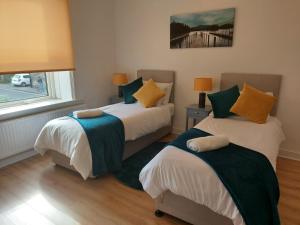 a bedroom with two beds with green and yellow pillows at Hilltop Place Suites Flat Above 250 in Sheffield