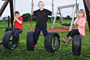 a man and two children sitting on tire swings at Aunt Rachel's Barn Hostel in Bushmills