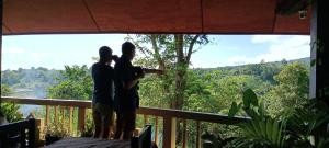 duas pessoas de pé numa varanda com vista para a floresta em Tangkoko Sanctuary Villa em Bitung