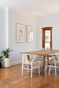 uma sala de jantar branca com uma mesa de madeira e cadeiras em Kuzman Homestead em Mudgee