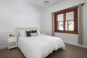 a white bedroom with a white bed and a window at Kuzman Homestead in Mudgee
