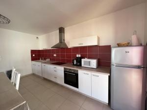 eine Küche mit einem Kühlschrank aus Edelstahl und roten Fliesen in der Unterkunft Appartement Les Sables-d'Olonne, 3 pièces, 4 personnes - FR-1-485-21 in Les Sables-dʼOlonne