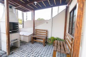 uma varanda com um banco de madeira e uma mesa em Apartamentos Bombinhas - 140 metros da Praia em Bombinhas