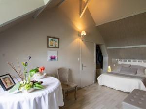 Un dormitorio con una cama y una mesa con flores. en Gîte charmant avec jardin et cheminée à 2 km de Cherveix-Cubas, proche sites préhistoriques et nautiques - FR-1-616-158, en Cherveix-Cubas