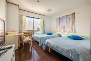 a bedroom with two beds and a desk and a window at MR. TOMO KAWANA in Kawana