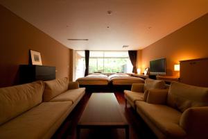 由布院ユウベルホテル في يوفو: غرفة معيشة مع أريكة وسرير
